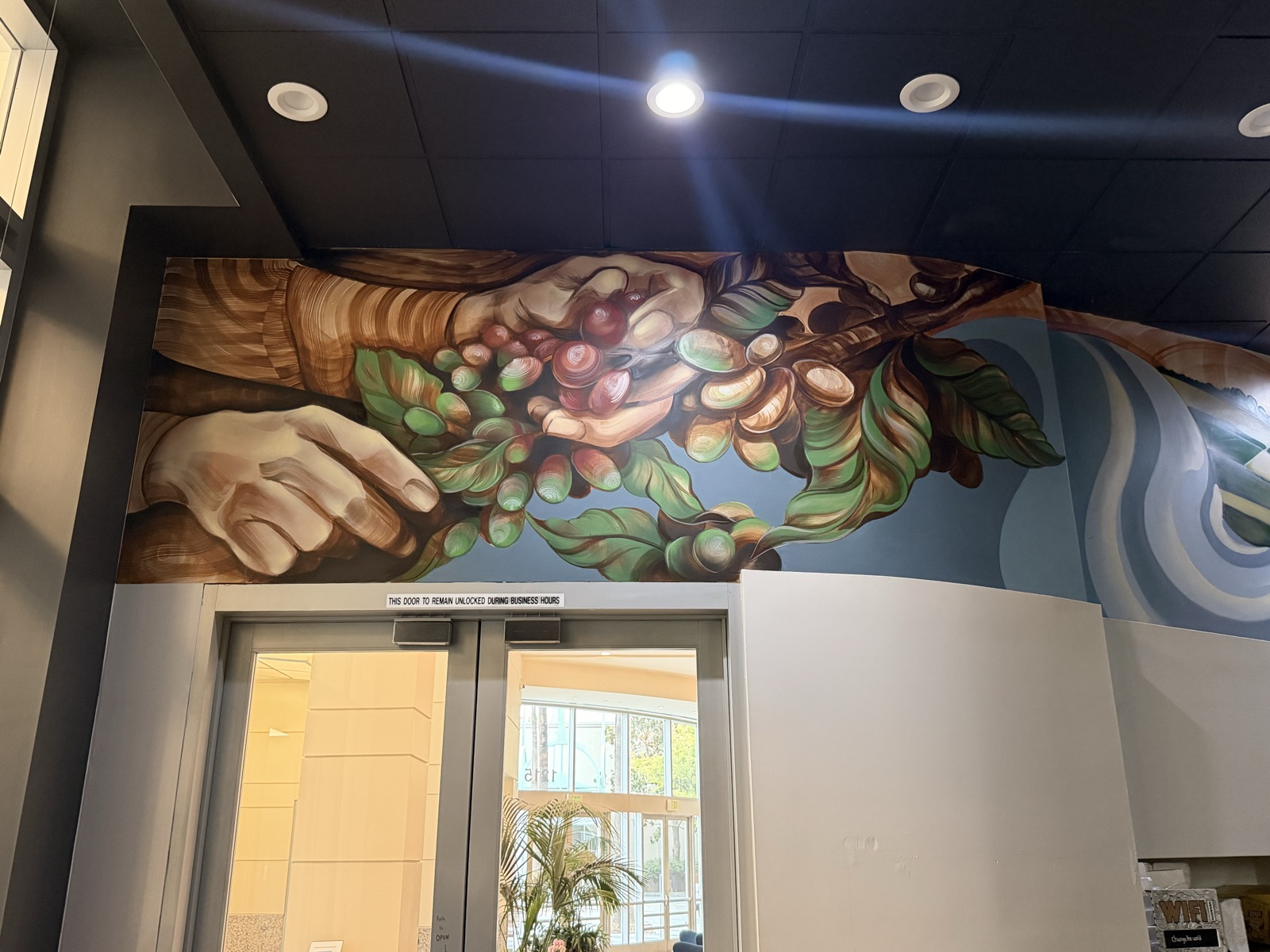 Mural of hands picking coffee cherries above the Grace Coffee Roasters entrance